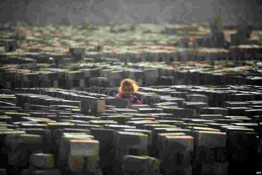 An Iraqi girl stands amid bricks being baked dry in the sun at a factory near the shrine city of Najaf. (AFP/Haidar Hamdani)