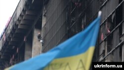 Робітник комунальних служб обрізає частини металевого каркасу залізобетонної конструкції Будинку профспілок, Київ, 1 квітня