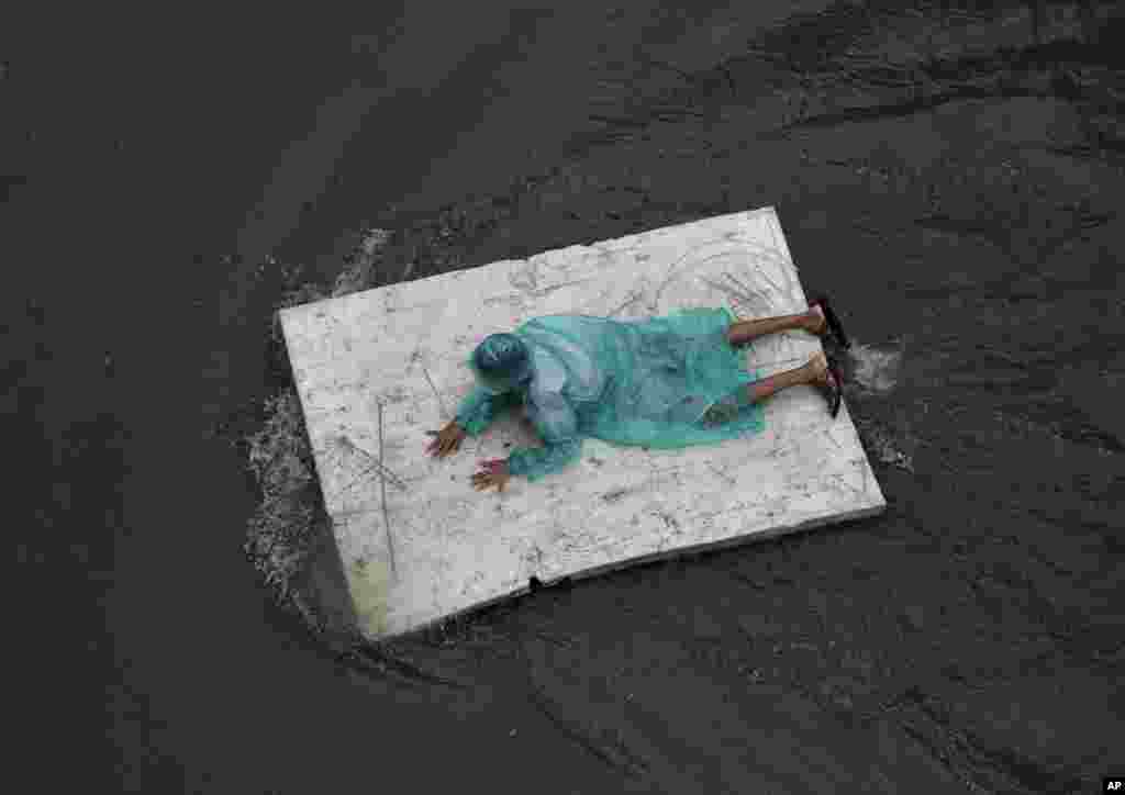 A boy floats on a plastic sheet on a a waterlogged street in Mumbai, India, on July 10. (AP/Rafiq Maqbool)