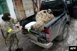 A Ukrainian serviceman wearing camouflage lies in a pickup truck as he prepares to take up a position on the front line near the southern city of Mariupol on January 26.