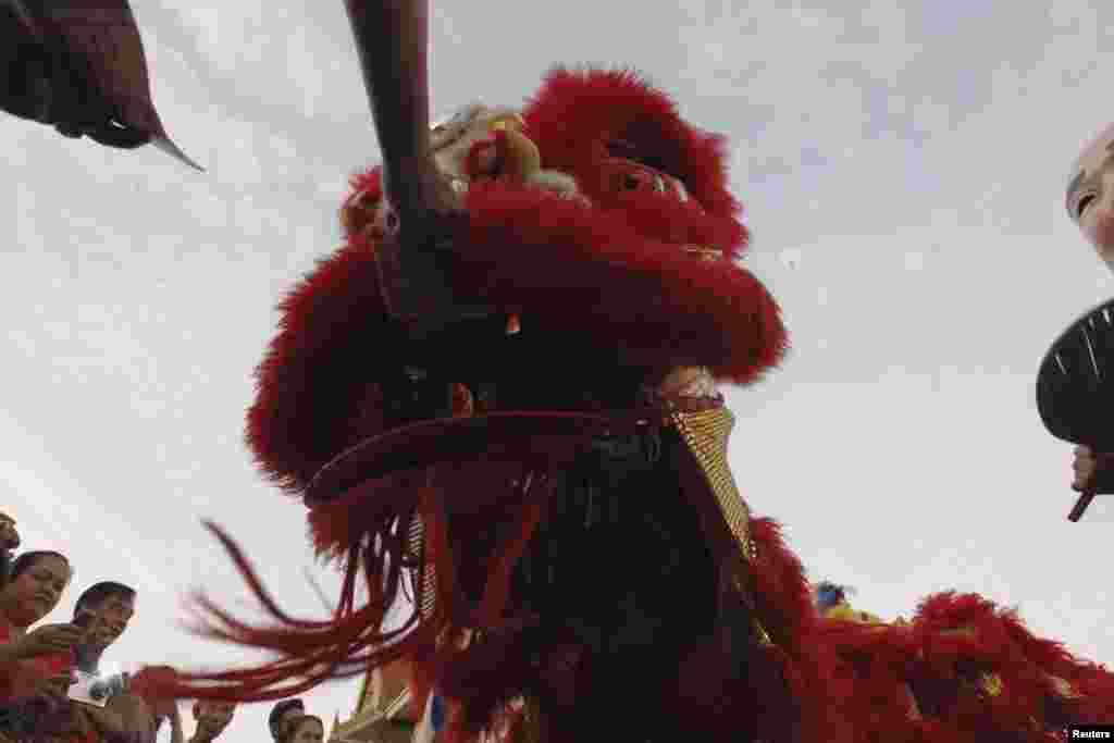 Ethnic Chinese Thais give money to a Chinese dragon puppet for Lunar New Year celebrations in Bangkok&#39;s Chinatown district.