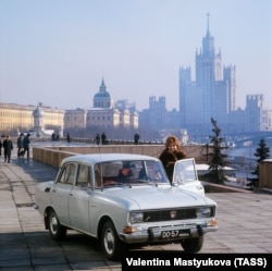 O femeie pozează lângă o mașină Moskvich, în Moscova, URSS, 1975.