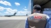 Uposlenik USAID-a gleda avion USAF C-17, koji se priprema za isporuku respiratora u Rusiju 