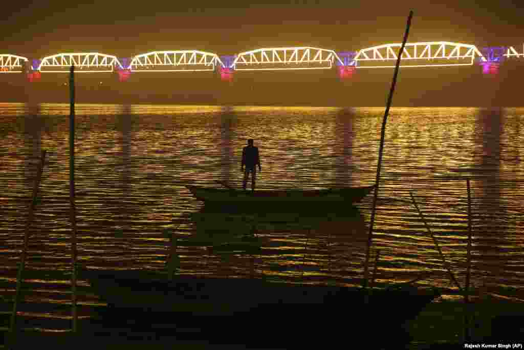 A person looks at an illuminated railway bridge across the Yamuna River ahead of the Kumbh Mela festival in Allahabad, India. Kumbh Mela is a 45-day festival attended by millions of Hindu devotees. They believe that taking a dip in the waters of the holy river will cleanse them of their sins. (AP/Rajesh Kumar Singh)