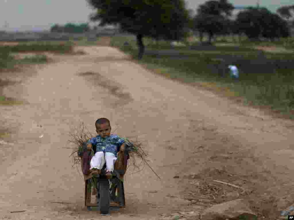 A Pakistani child sits in a wheelbarrow loaded with wood on the outskirts of Islamabad, Pakistan. (Photo by Muhammed Muheisen for AP) 
