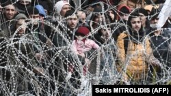 Această fotografie, făcută din partea grecească a a punctului de trecere a frontierei dintre Grecia și Turcia din apropiere de Kastanies, arată migranți așteptând în partea turcească a graniței, 2 martie 2020.