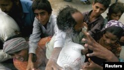 Flood victims scramble for sacks of flour distributed by volunteers in the outskirts of Karachi on August 16.