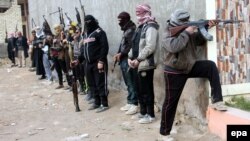 Sunni fighters carry RPG missile launcher and machine guns as they take up position in Fallujah city on January 5.