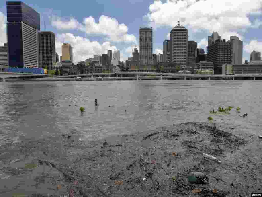 The swollen Brisbane River is seen flowing past the skyline of central Brisbane January 12, 2011. Thousands of residents of Australia's third-largest city evacuated homes on Wednesday as massive floods began to inundate the financial district, sparked panic buying of food and left authorities despairing for more than 90 people missing. REUTERS/Mick Tsikas (AUSTRALIA - Tags: DISASTER ENVIRONMENT)