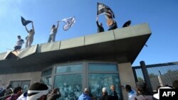 Tunisian protesters break windows as they hold Islamic flags above the gate of the U.S. Embassy compound in Tunis during a protest against the film on September 14.