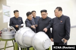 Солтүстік Корея басшысы Ким Чен Ын (ортада) ядролық қарудың макетін қарап тұр. Ресми сурет.