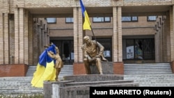 Ukrainian flags are displayed on a statue of Taras Shevchenko in the center of the city of Balaklia in the Kharkiv region after it was liberated from Russian forces.