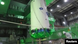 A cask of nuclear fuel is lifted and moved by workers during operations to remove fuel rods from a spent fuel pool inside the No.4 reactor building at Tokyo Electric Power Co's (TEPCO) Fukushima Daiichi nuclear power plant on November 18.