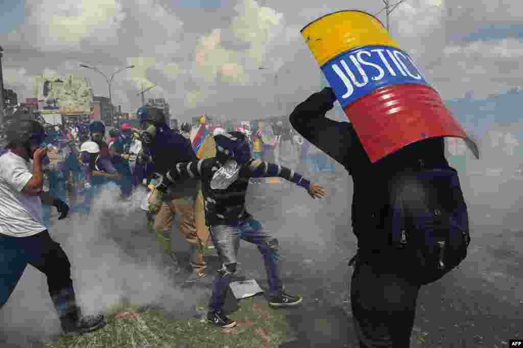 A demonstrator takes cover behind a makeshift shield as clashes with riot police erupt, during a march against President Nicolas Maduro in Caracas, Venezuela, on May 10. (AFP/Juan Barreto)