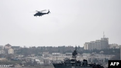 Ukraine -- A Russian Mi24 military helicopter flies over the Russian navy minesweeper ship "Turbinist" in the harbor of Sevastopol, March 7, 2014