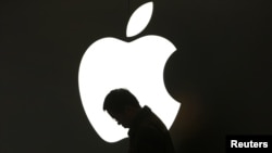 Apple белгісінің алдында iPad қарап отырған адам. Қытай, 16 наурыз 2012 жыл.