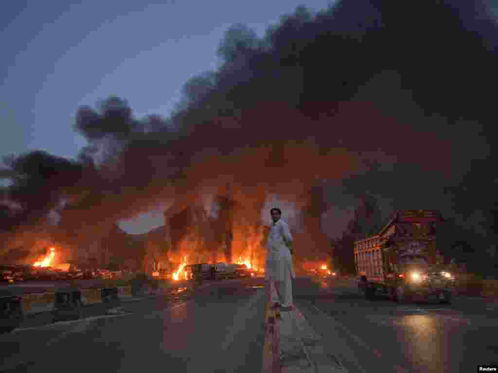 A local resident stands on the street median as he watches fuel tankers burn along the road in Nowshera, in Pakistan's Khyber-Pakhtunkhwa Province, on October 7. Photo by Adrees Latif for Reuters