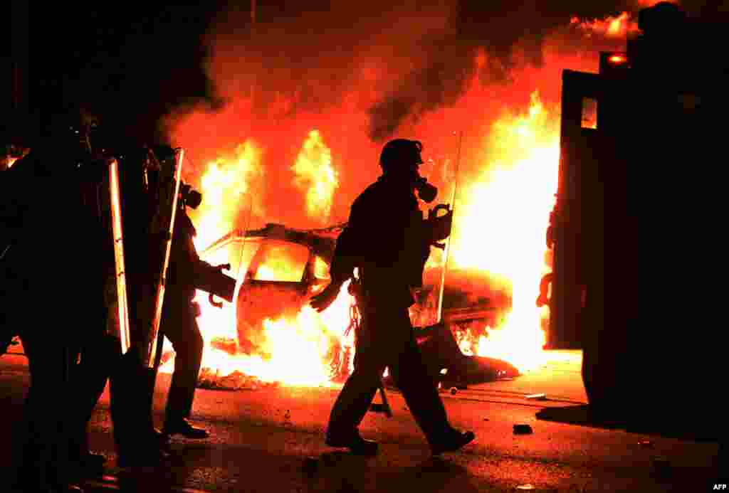 Police chase protesters as a car burns during rioting following a controversial grand jury decision concerning the death of 18-year-old Michael Brown in Ferguson, Missouri, in the United States. (AFP/Jewel Samad)