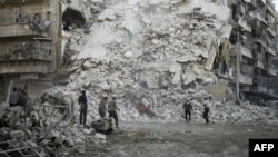 Members of the Syrian Civil Defense, known as the White Helmets, search for victims amid the rubble of a destroyed building following reported air strikes in the rebel-held Qatarji neighborhood of the northern city of Aleppo on October 17.