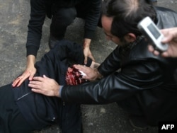 Iranian protesters wipe the bloodied face of a man who was believed to have been shot during anti-government rallies in Tehran on December 2009.