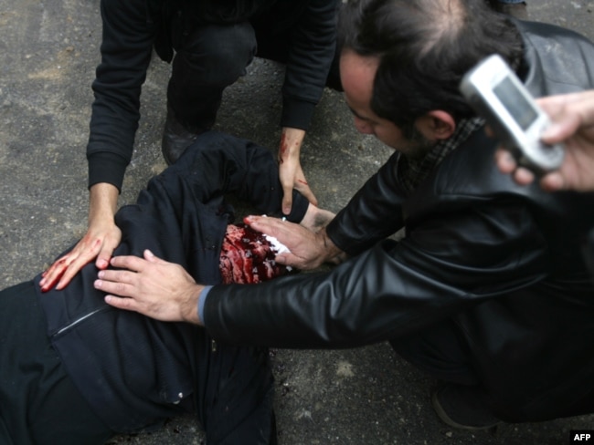 Iranian protesters wipe the bloodied face of a man who was believed to have been shot during anti-government rallies in Tehran on December 2009.