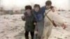 Двое чеченских бойцов несут раненного в результате обстрела на окраине Грозного 25 декабря 1994 года, когда российские вооруженные силы усилили бомбардировку города