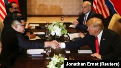 АҚШ президенті Дональд Трамп пен Солтүстік Корея басшысы Ким Чен Ын кездесуде қол алысып отыр. Сингапур, 12 маусым 2018 жыл.