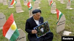 أب يحمل صورة ابنه في مقبرة لضحايا حلبجة