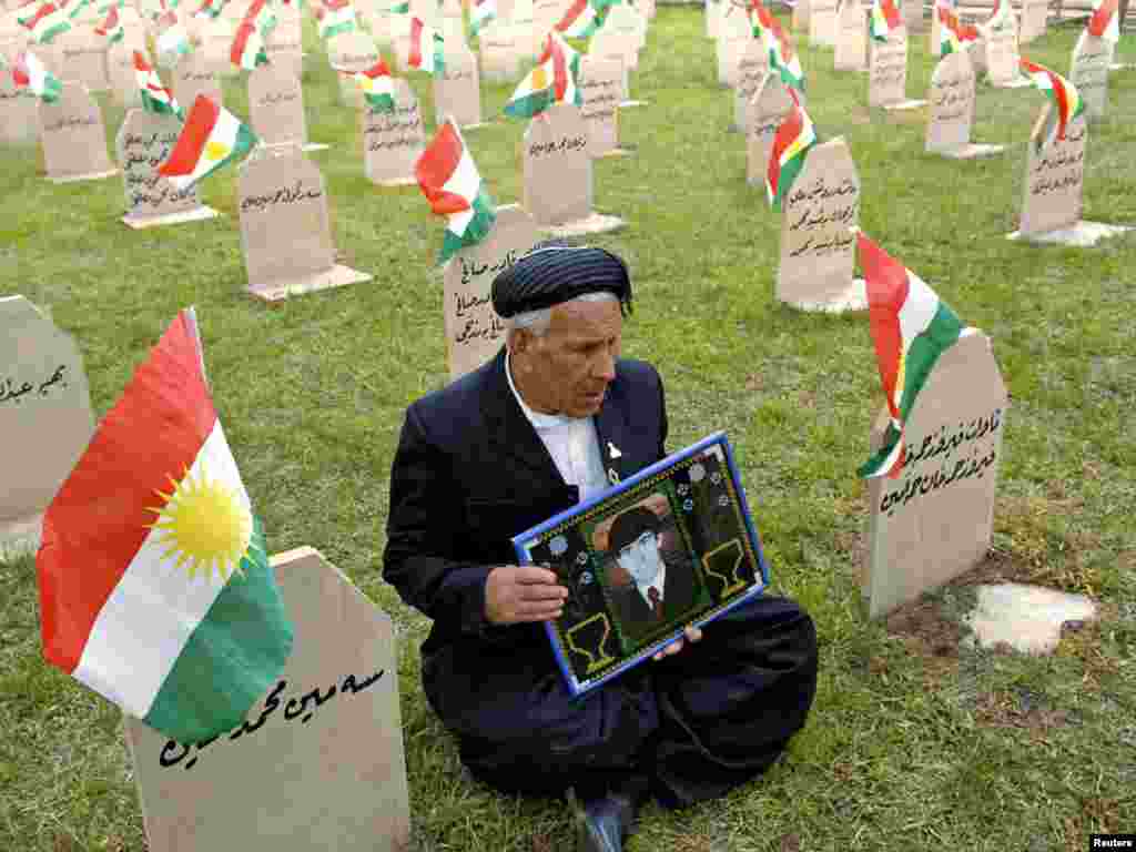 A man holds a picture of his son at a cemetery for victims of the poison gas attack on Kurds in Halabjah, northern Iraq. - Iraqi Kurds on March 16 commemorated the anniversary of the 1988 attack by Saddam Hussein's regime, in which thousands died. Photo by Jamal Penjweny for Reuters