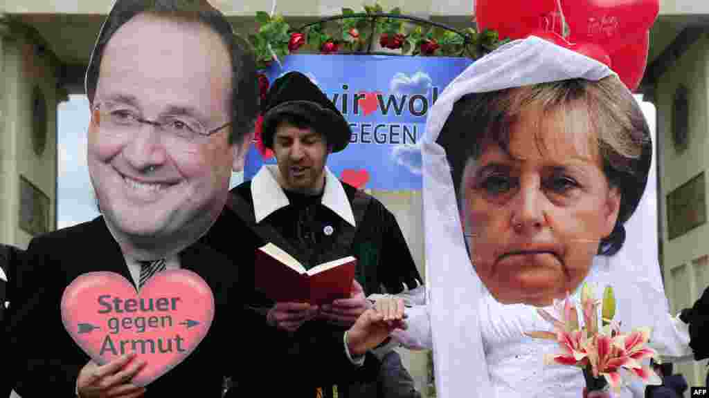 Activists wear masks depiting German Chancellor Angela Merkel and incoming French President Francois Hollande as they perform a fake marriage in front of the Brandenburg Gate in Berlin. (AFP/John MacDougall)