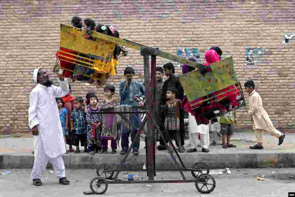 Pakistani children ride a seesaw during the Eid al-Fitr celebrations in Peshawar, Pakistan. (epa/Bilawal Arbab)&nbsp;