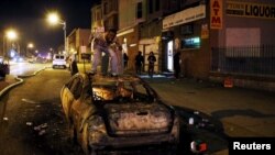 U.S. -- A rioter screams from atop a burning car during clashes in Baltimore, Maryland April 27, 2015.