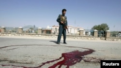 A police officer stands guard near bloodstains on the ground at the site of the bomb blast in Ghazni Province.