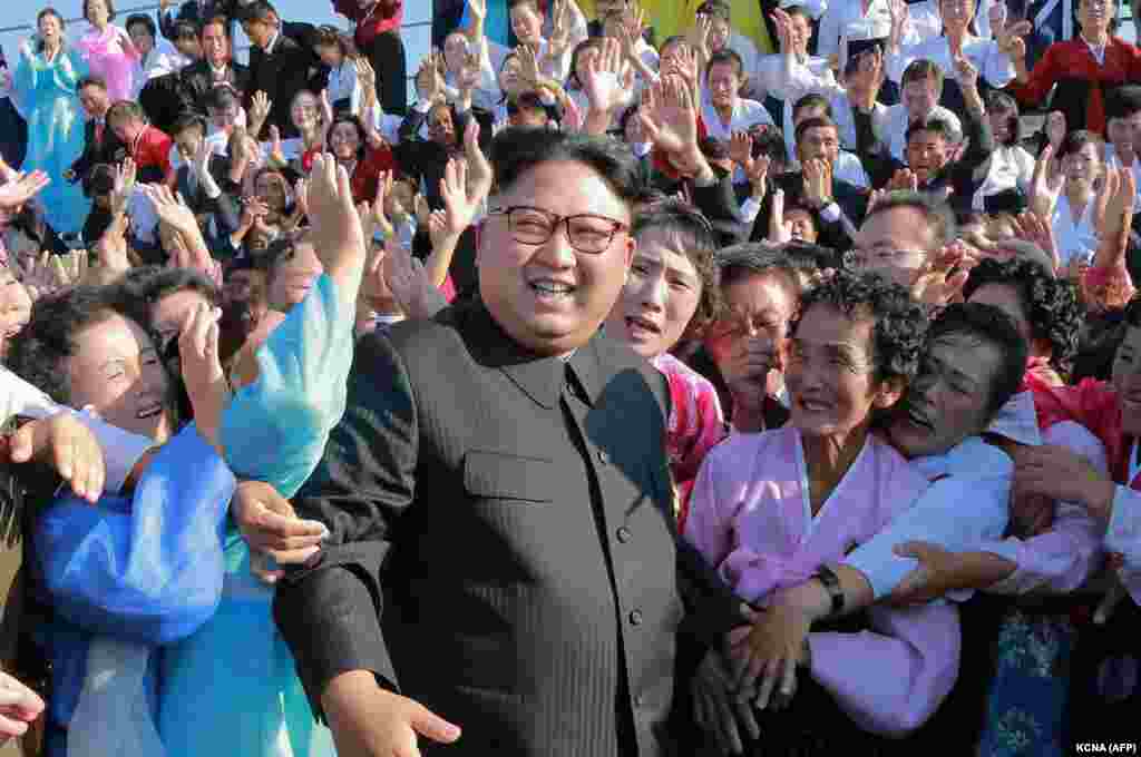 Demirgazyk Koreýanyň lideri Kim Jong Un Phenýanda adalardaky we daglyk ýerlerdäki mekdeplerde işlemäge meýletinlik bildiren mugallymlar bilen surata düşýär. &nbsp;(AFP/KCNA via KNS)