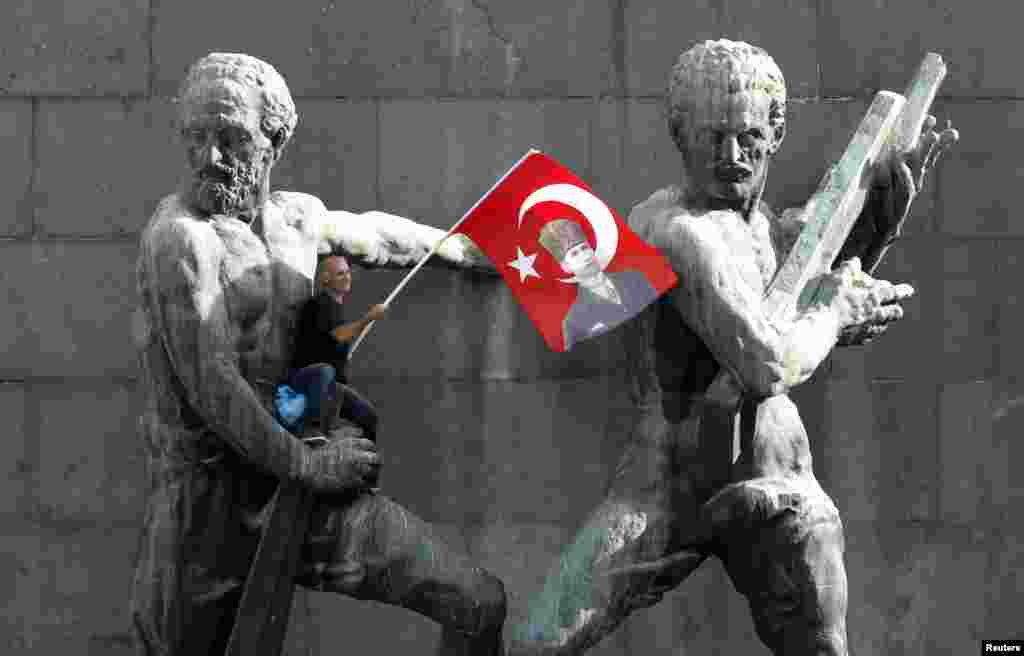 A demonstrator waves the Turkish national flag as he sits on a monument during a protest against Prime Minister Recep Tayyip Erdogan and his ruling AK Party in central Ankara. (Reuters/Umit Bektas)