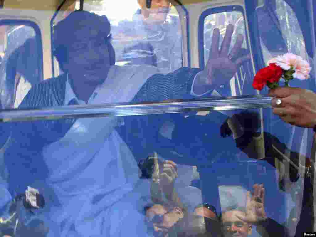 Libyan leader Muammar Qaddafi waves from his personal vehicle in Tripoli on March 2. Photo by Ahmed Jadallah for Reuters