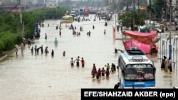 People make their way on an flooded street after heavy rain in Karachi on August 31.