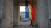 A woman walks under the Triumphal Arch next to the Moldovan flag in Chisinau.