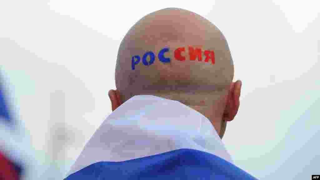 A Russian football fan with &quot;Russia&quot; painted on his head outside the stadium in Warsaw