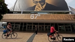 Люди проезжают на велосипедах мимо официального плаката 67-го Каннского кинофестиваля. 12 мая 2014 года.
