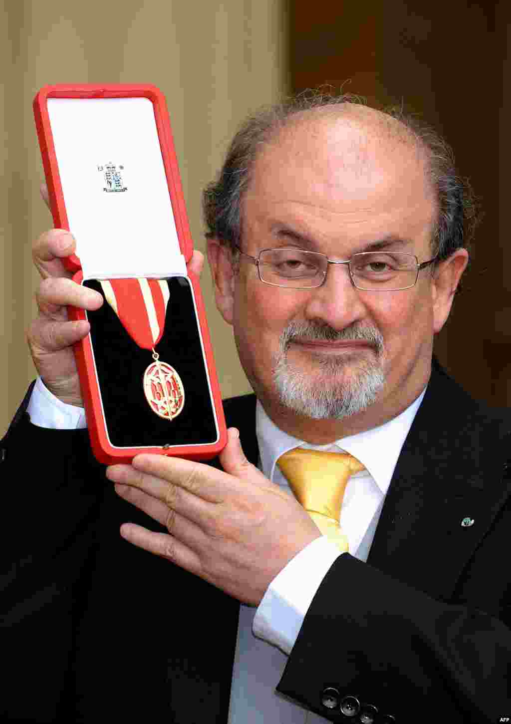 Sir Salman Rushdie poses for photographs after receiving his knighthood for his service to literature from Britain's Queen Elizabeth II at Buckingham Palace in London on June 25, 2008.