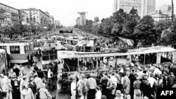 Oamenii se adună în fața unei baricade formată din tramvaie la locul ciocnirilor dintre forțele de ordine și protestatari, 21 august 1991.