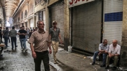 People walk through the old grand bazaar where shops are closed after a protest, in Tehran, Iran, June 25, 2018.