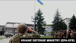 Ukrainian soldiers salute a newly hoisted Ukrainian flag in the city of Balaklia, Kharkiv region, which was liberated on September 10.
