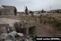 Tunisian women cross over a trench full of garbage in the poverty-stricken town of Douar Hicher, northeast of Tunis.