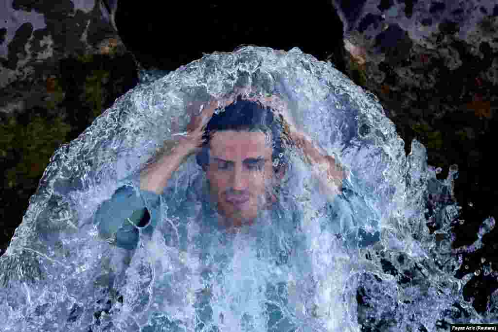 A man cools off under a water pipe on the outskirts of Peshawar, Pakistan. (Reuters/Fayaz Aziz)