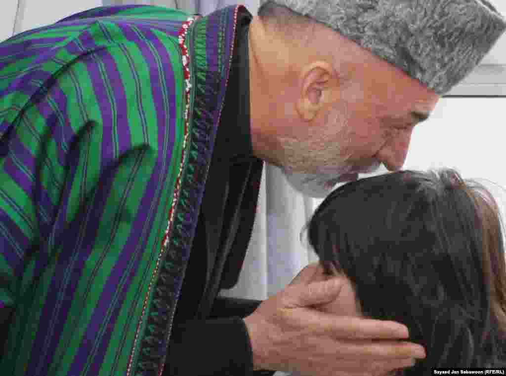 Afghanistan -- President Hamid Karzai kisses the head of a girl who was wounded in prevoius day's suicide bomb attack during an Ashura mourning procession, as he visits victims at the Emergency Hospital in Kabul, 07Dec2011