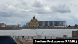 An Orthodox church stands in front of the Nizhny Novgorod football stadium.