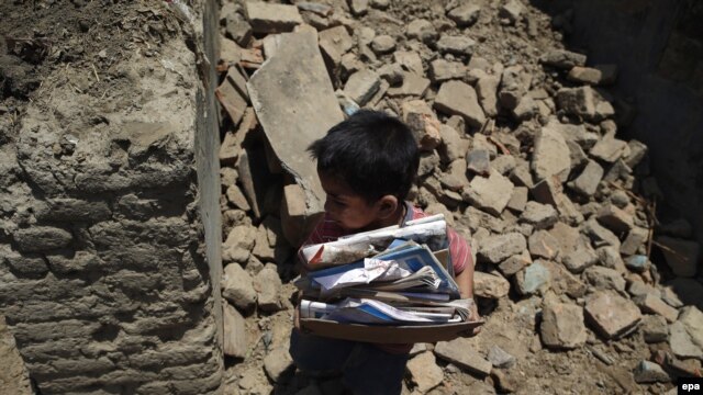 Petogodišnji dječak Arus skuplja svoje knjige iz kuće nakon zemljotresa