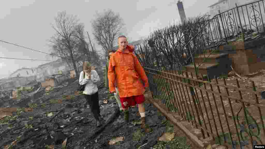 Keith Klein and Eileen Blair walk among homes devastated by fire and the effects of Hurricane Sandy in the Breezy Point section of Queens, New York.